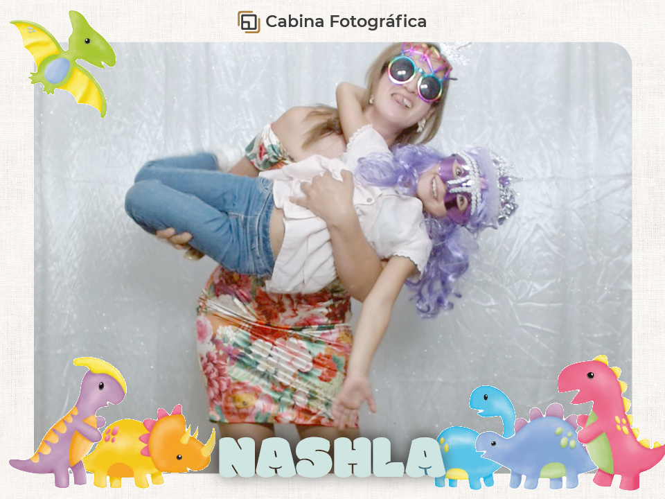 "Niños sonriendo con divertidos props de dinosaurios frente a la cabina fotográfica de Snap Memory en un cumpleaños infantil.